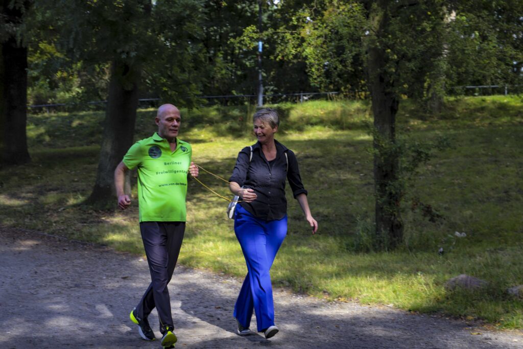 Jörg von de Fenn und Bezirksbürgermeisterin Cordelia Koch laufen Tandem am Weißen See. 